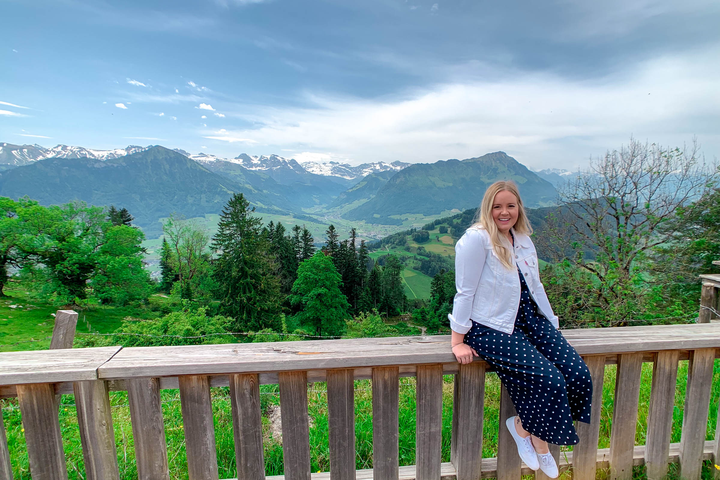 Madison sitting on fence with Swiss mountains in the background